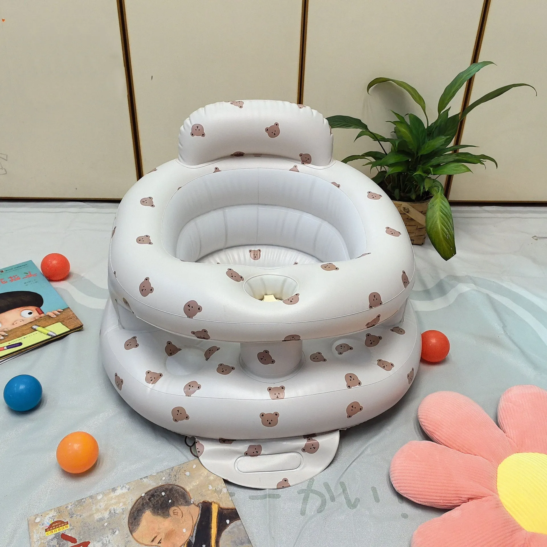 Inflatable infant dining chair in PVC with bear design, deflated beside a baby for scale
