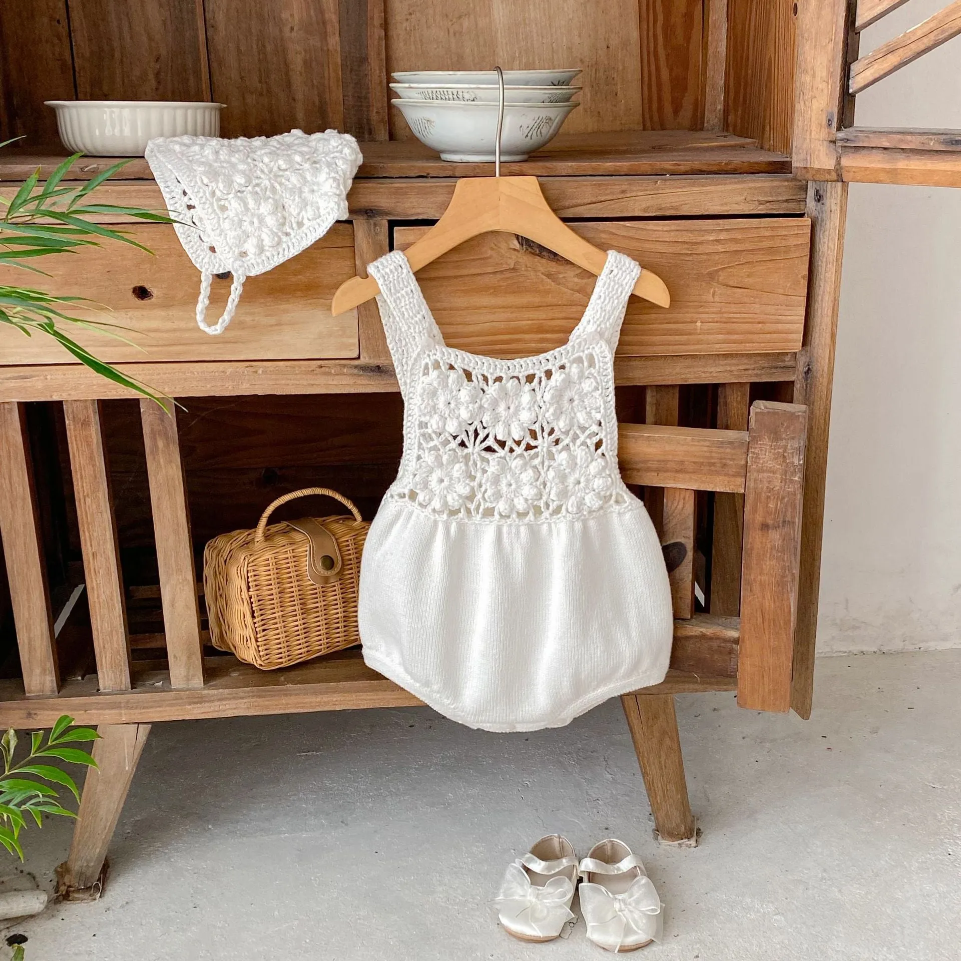 Beige baby romper with flower cutout strap and matching hat on a baby girl