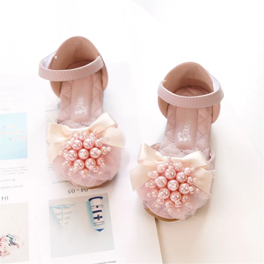 Girls princess-style sandals in beige with peep toe, pearl flower detail, and Velcro strap on a white background