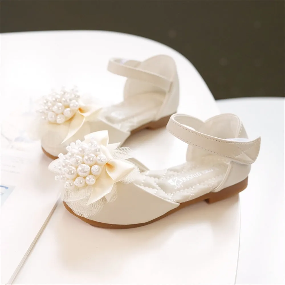 Girls princess-style sandals in beige with peep toe, pearl flower detail, and Velcro strap on a white background