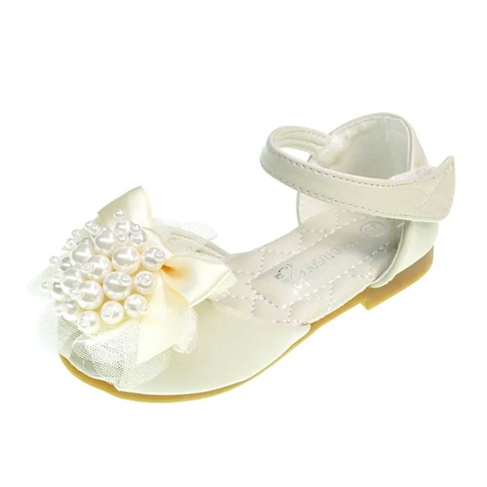 Girls princess-style sandals in beige with peep toe, pearl flower detail, and Velcro strap on a white background