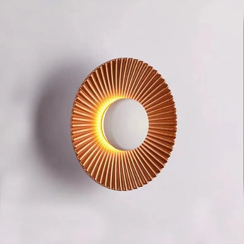 Round aluminium wall lamp in an outer white and inner gold colour combination, mounted on a wall.