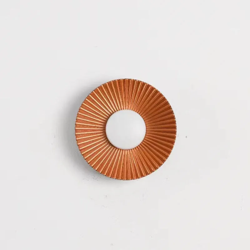 Round aluminium wall lamp in an outer white and inner gold colour combination, mounted on a wall.
