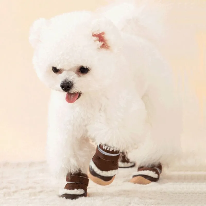 Brown winter dog shoes with adjustable Velcro straps and anti-slip rubber soles on a snowy surface