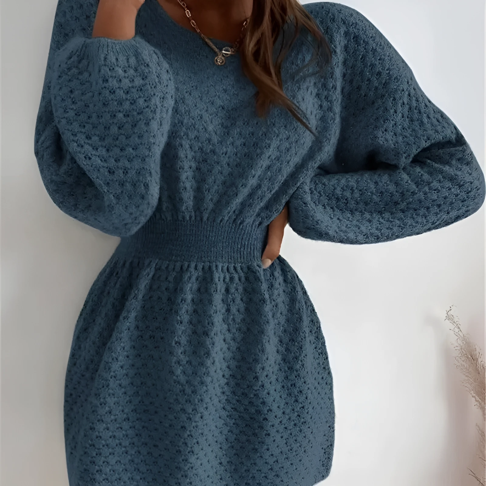 Blue women's knitted dress with crocheted flower details, round neck, fitted waist, and long sleeves.
