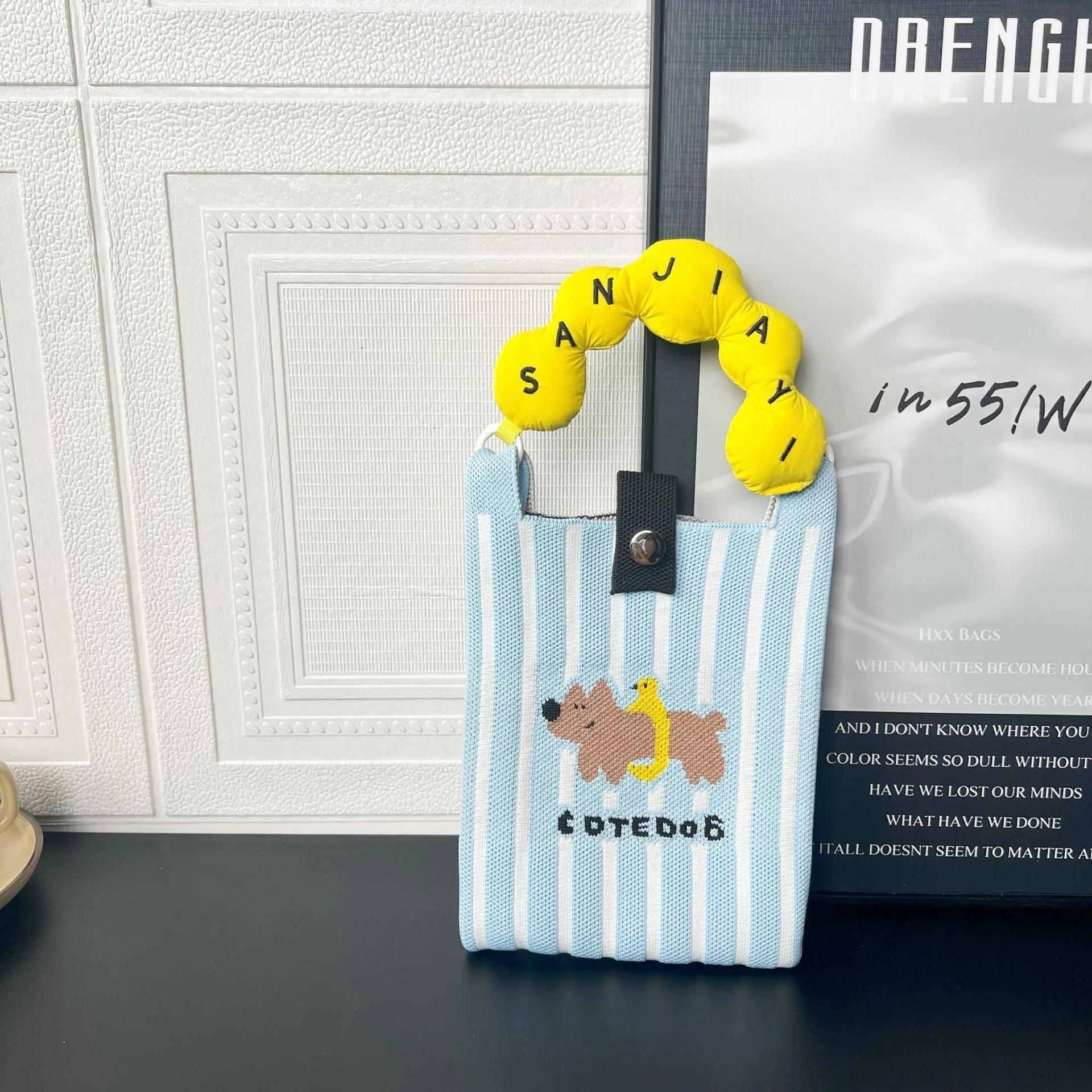 Square-shaped knitted polyester messenger bag featuring a cartoon character design, shown with an open outer pocket and adjustable shoulder strap.