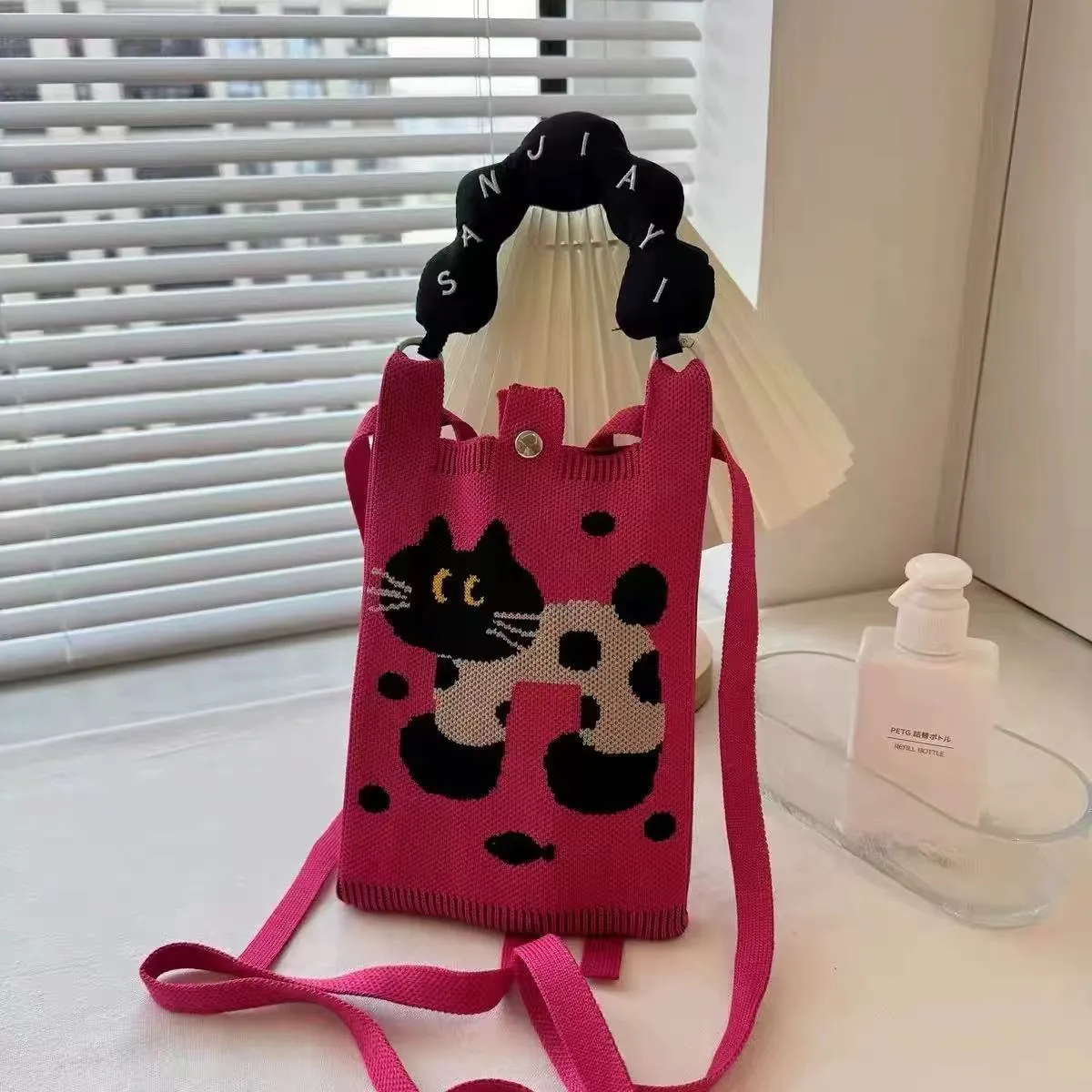 Square-shaped knitted polyester messenger bag featuring a cartoon character design, shown with an open outer pocket and adjustable shoulder strap.