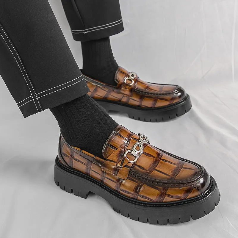 Men's black crocodile pattern loafers with a flat platform sole on a plain background.