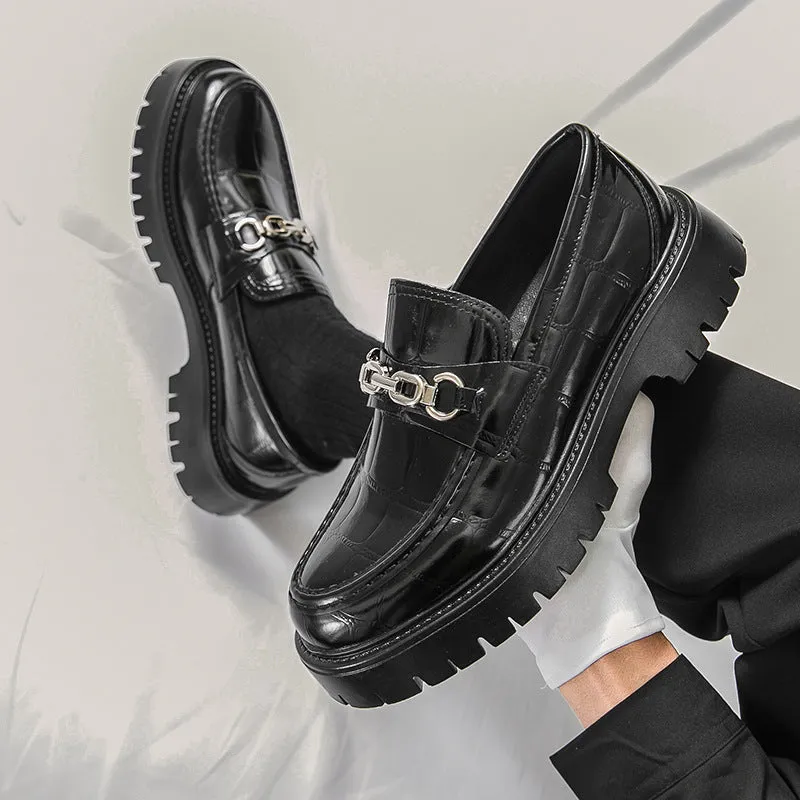 Men's black crocodile pattern loafers with a flat platform sole on a plain background.