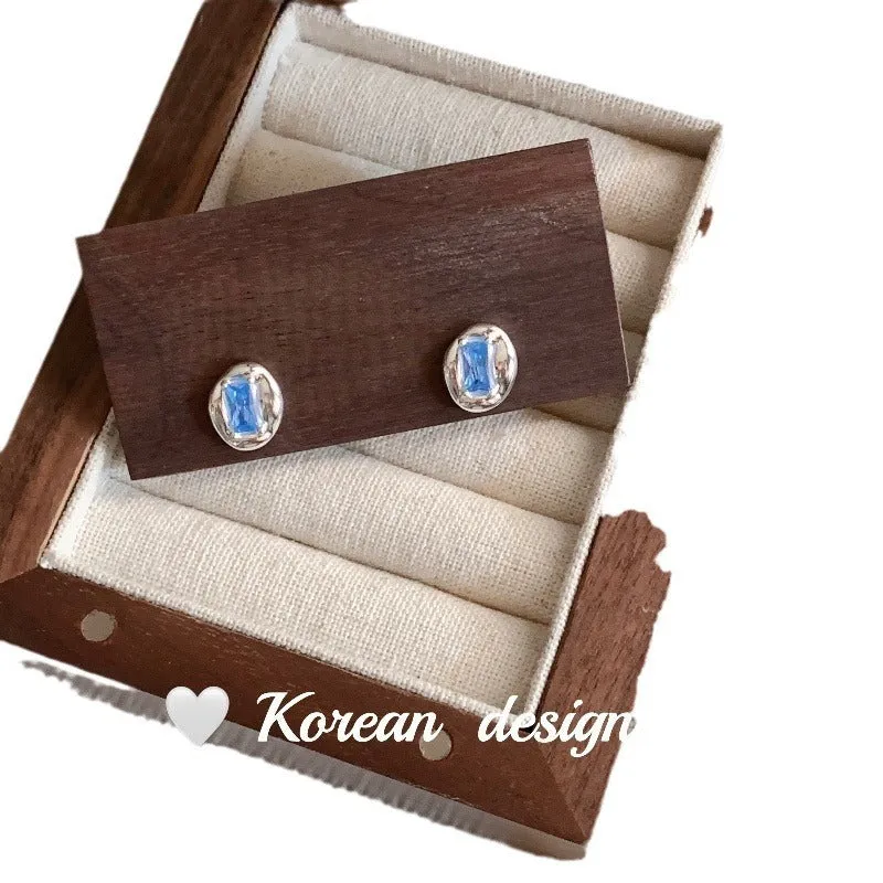 Sterling silver earrings with heart-wrapped oval blue diamond design and electroplated finish