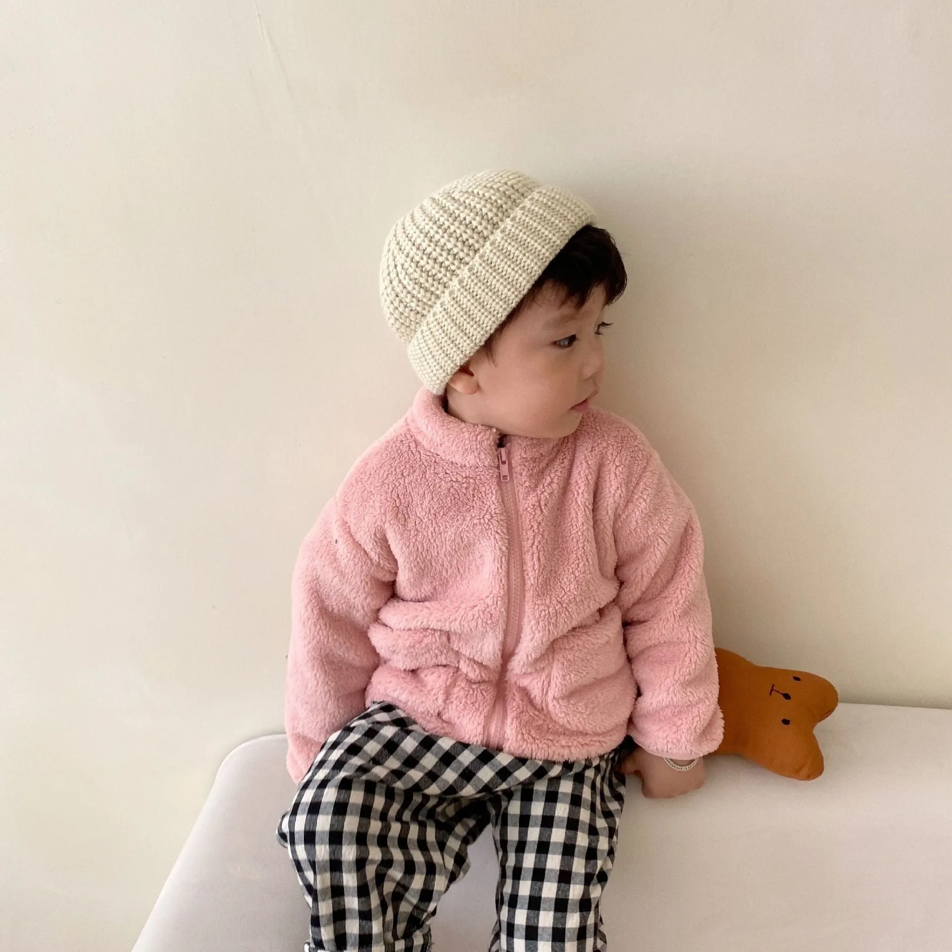 A child's blue sherpa fleece jacket with a full zip, high collar, and front pockets on a hanger.