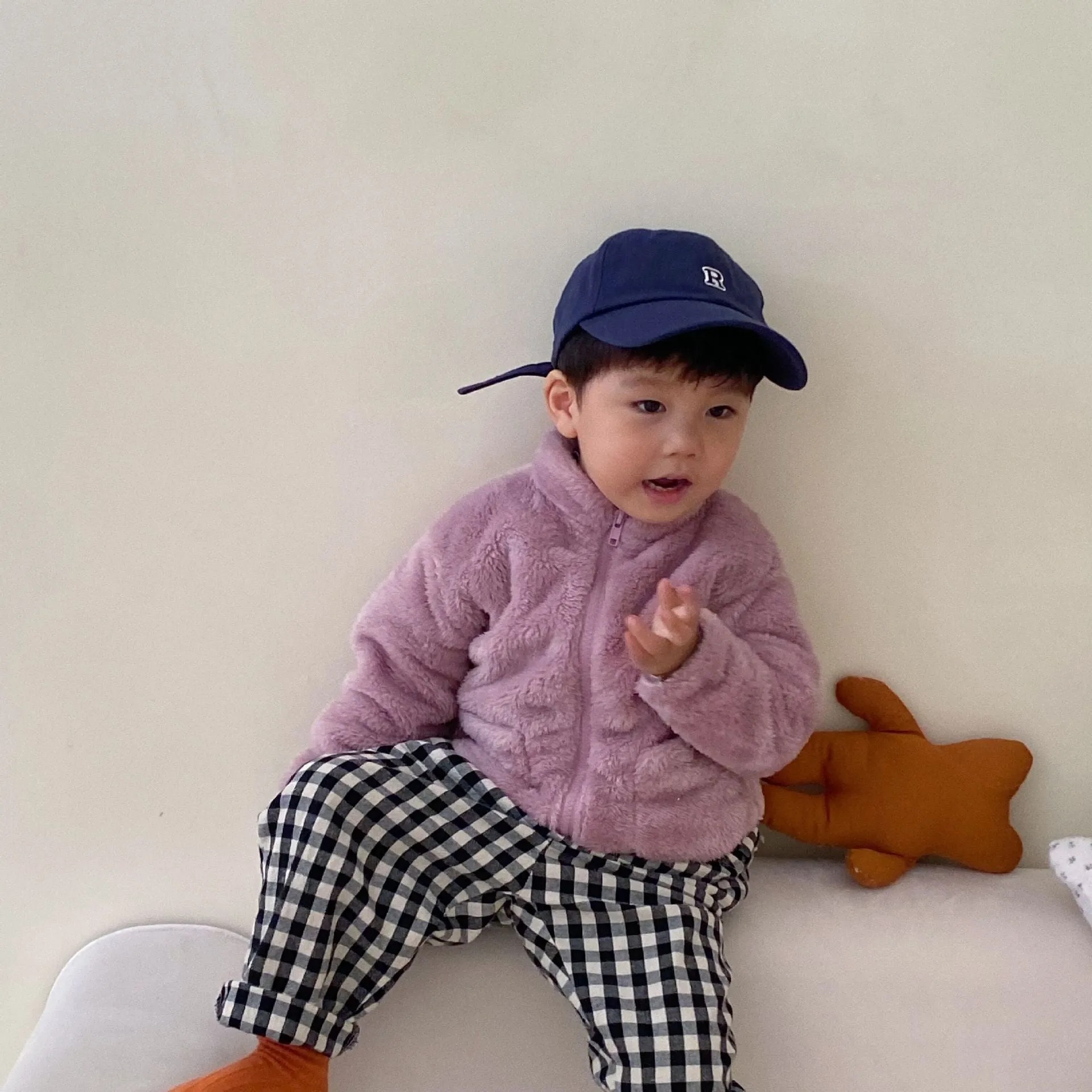 A child's blue sherpa fleece jacket with a full zip, high collar, and front pockets on a hanger.