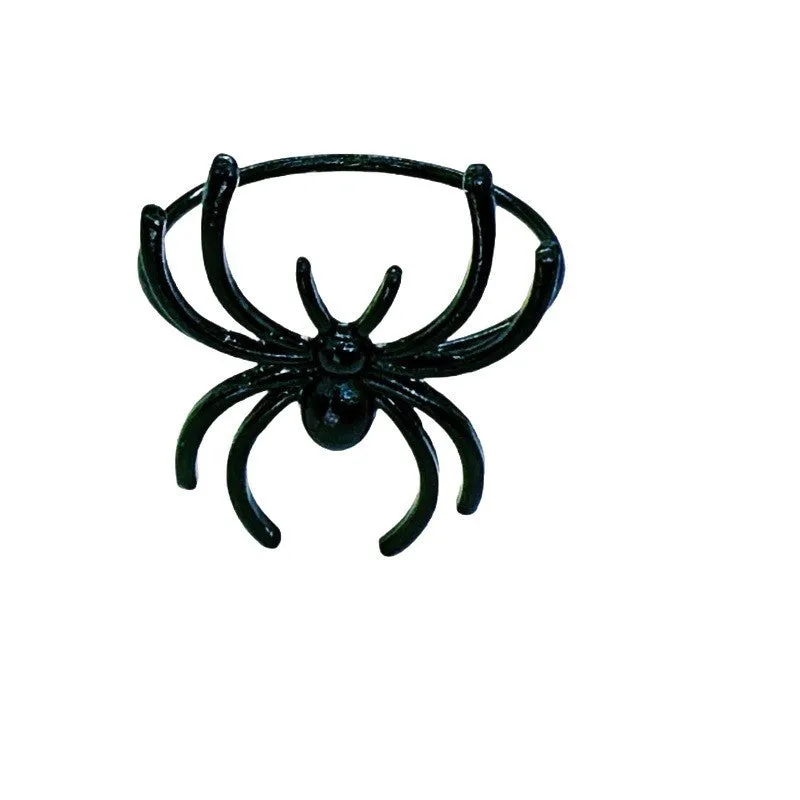 Set of six black alloy spider-shaped napkin rings on a dark tablecloth.