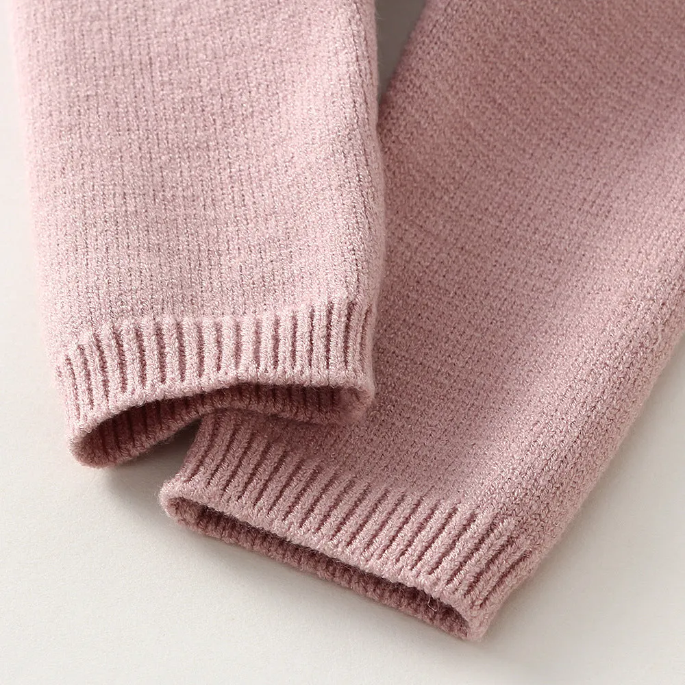 Baby girl wearing a pink knitted pullover sweater and matching trousers set.