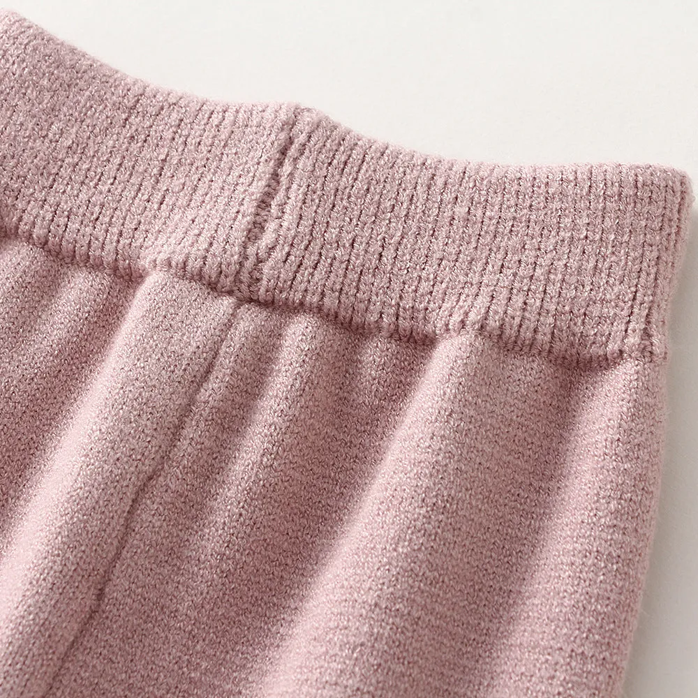 Baby girl wearing a pink knitted pullover sweater and matching trousers set.