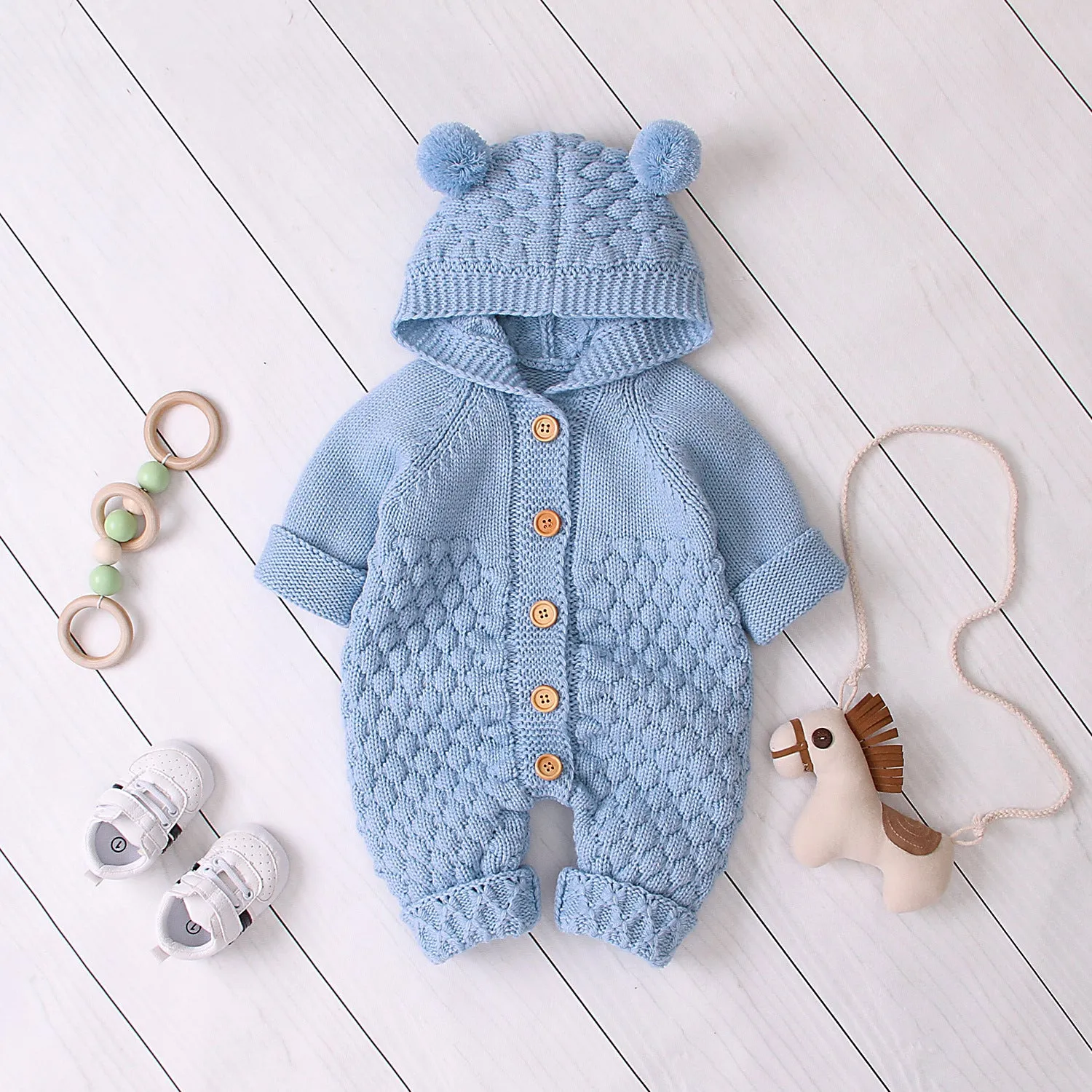 Adult wearing a blue knitted hooded jumpsuit with long sleeves and a single-breasted closure.