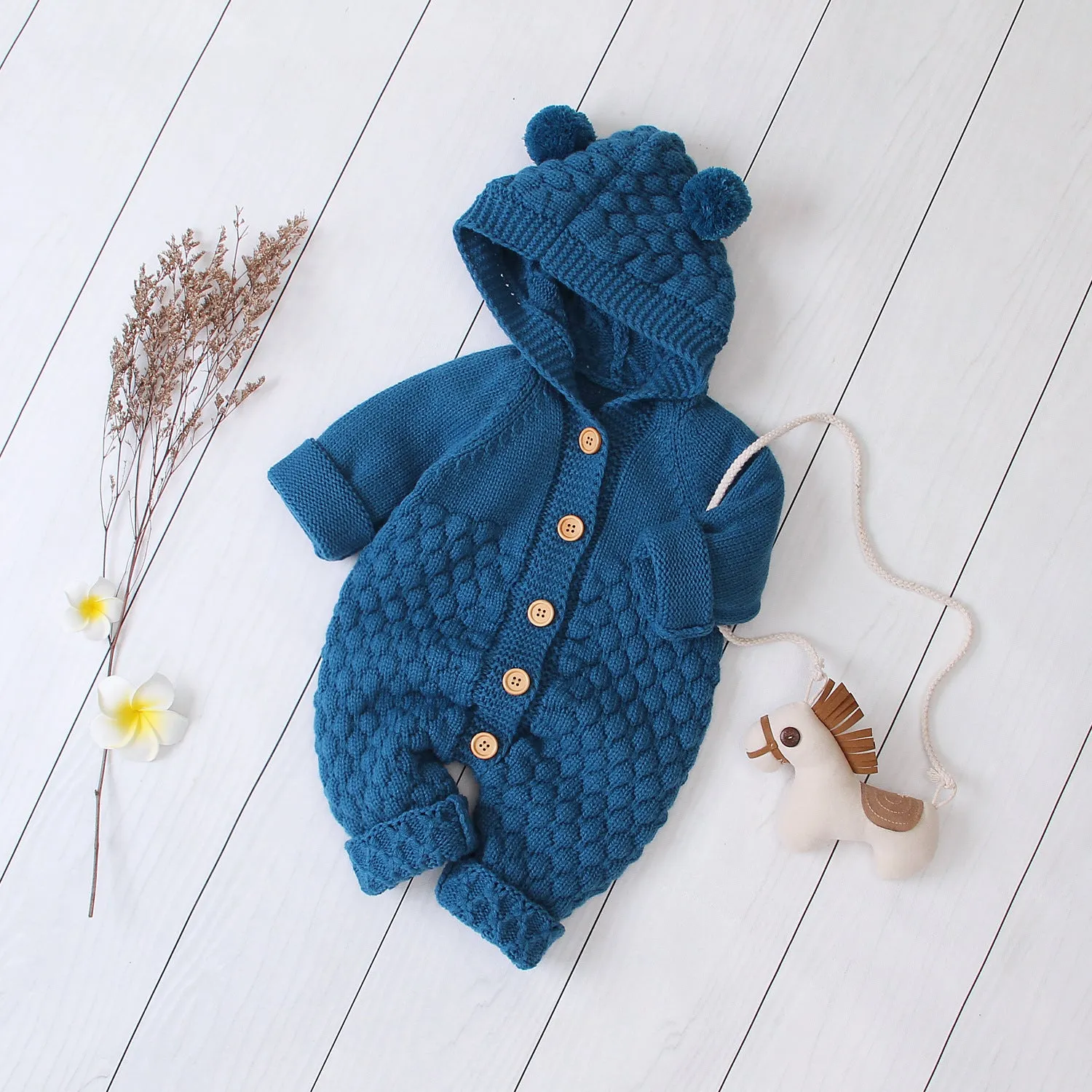 Adult wearing a blue knitted hooded jumpsuit with long sleeves and a single-breasted closure.