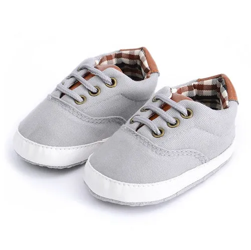 Solid colour baby canvas shoes with a front strap, shown in light grey on a white background.