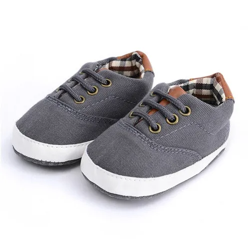 Solid colour baby canvas shoes with a front strap, shown in light grey on a white background.