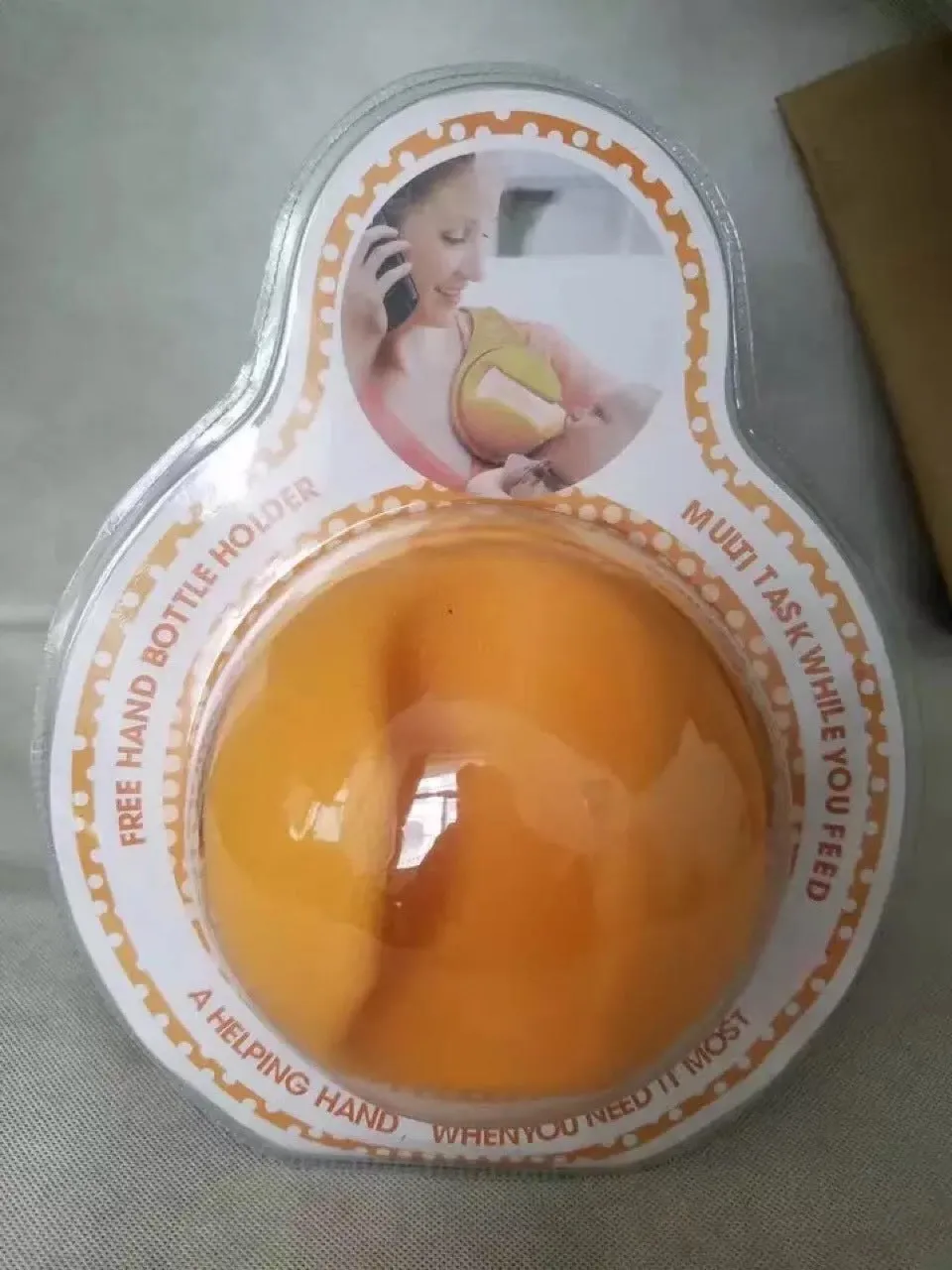Yellow plastic hands-free baby bottle holder on a white surface, showing the bottle slot and ergonomic curve, 48x16x13cm
