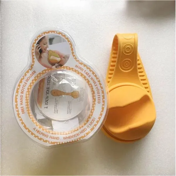 Yellow plastic hands-free baby bottle holder on a white surface, showing the bottle slot and ergonomic curve, 48x16x13cm