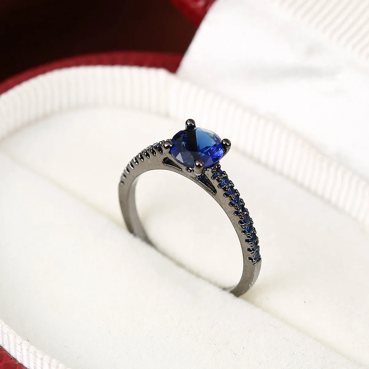 Hexagonal geometric zircon ring in copper with an electroplated gun black purple finish on a finger.