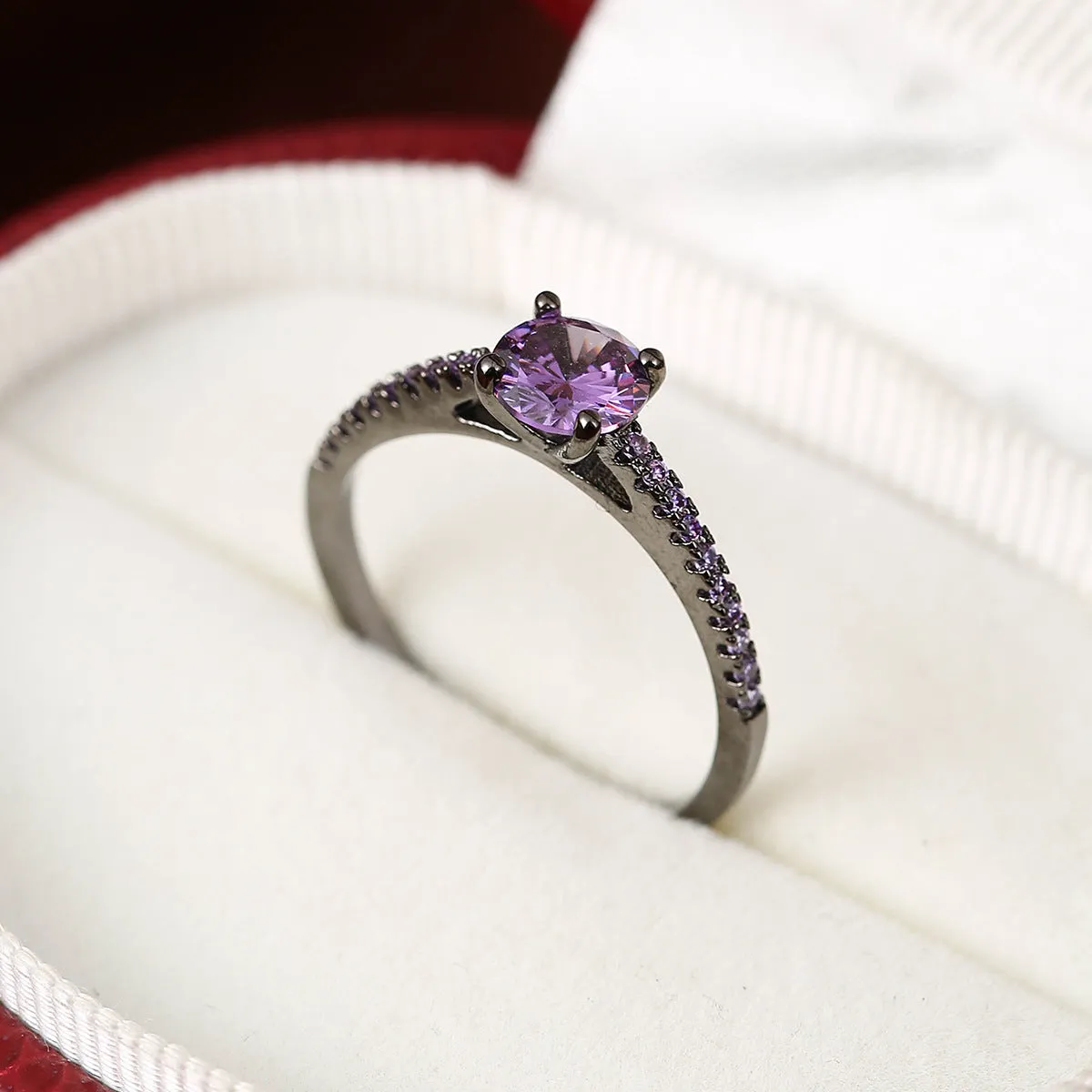 Hexagonal geometric zircon ring in copper with an electroplated gun black purple finish on a finger.