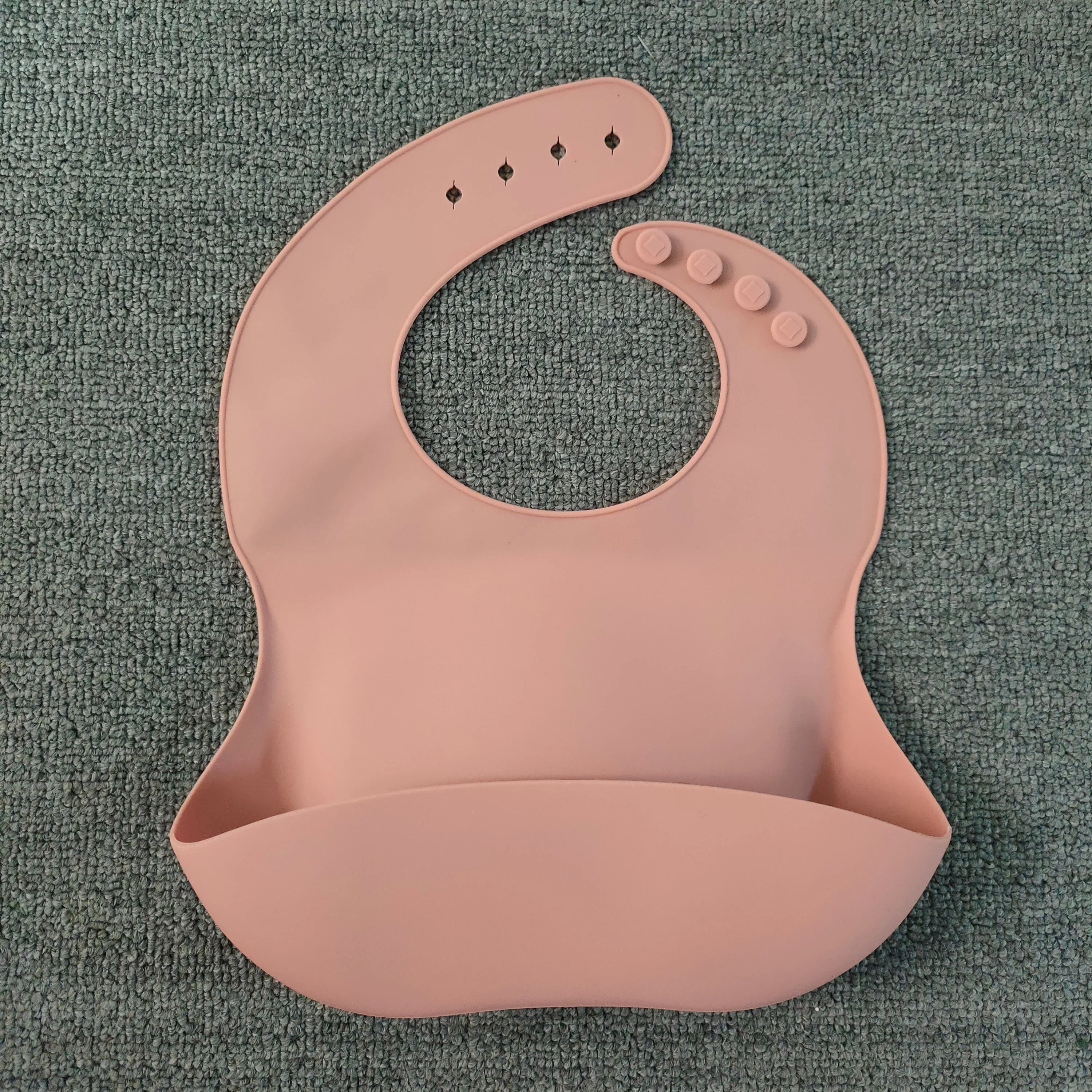 Soft waterproof silicone baby bib with food catcher in pink, with adjustable neck closure