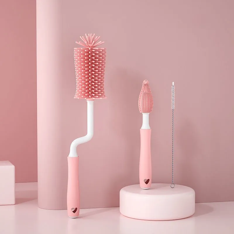 Three silicone baby bottle brushes in blue, pink, and yellow with straw scrubber on white background