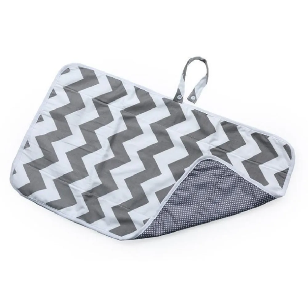 Portable baby diaper changing mat in yellow geometric pattern, 70x50cm, with toy ring and wrist strap unfolded on floor