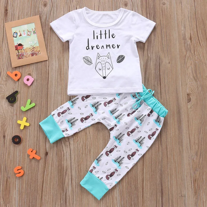 Newborn baby clothes set with white cotton T-shirt and grey pants on a soft background
