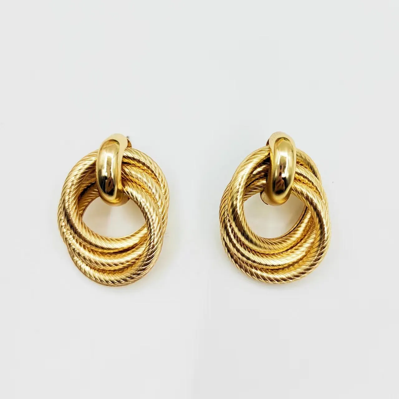 Gold metal geometric ring embossed twisted stud earrings on display