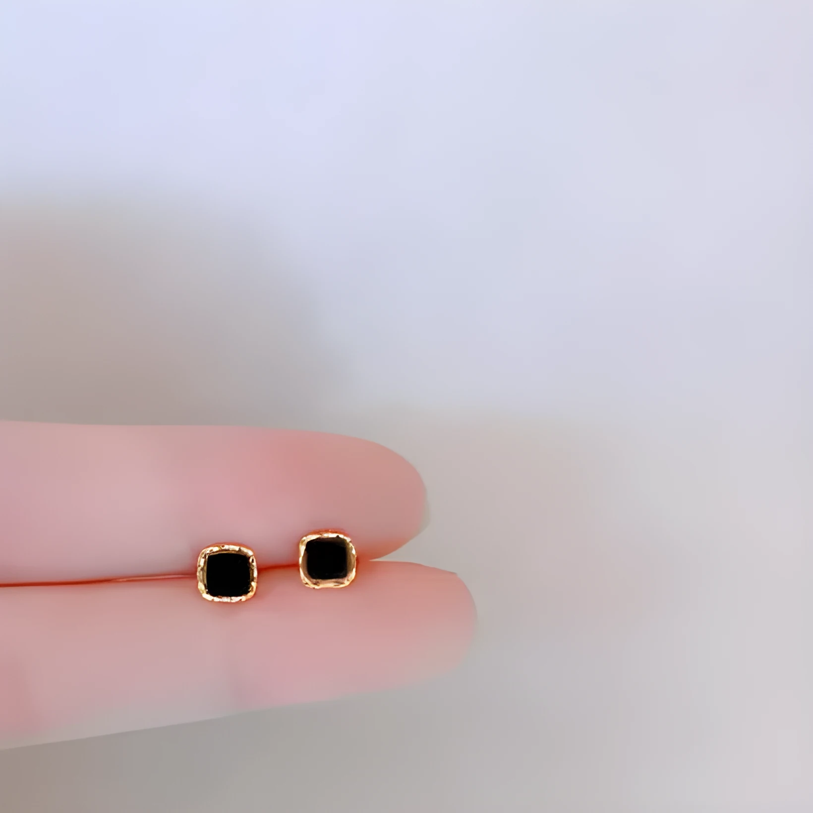 Black round mini ear studs in sterling silver plating with inlaid zircon on white background