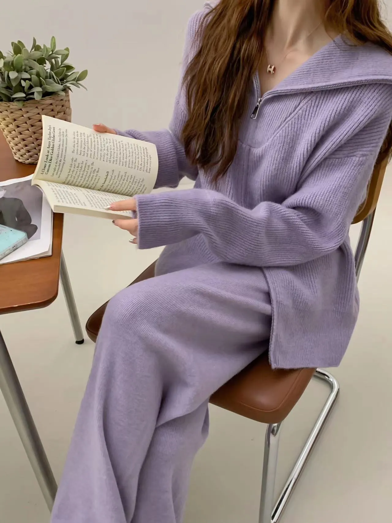 Woman wearing a knitted zipper cardigan and wide-leg trousers from a solid colour two-piece set.
