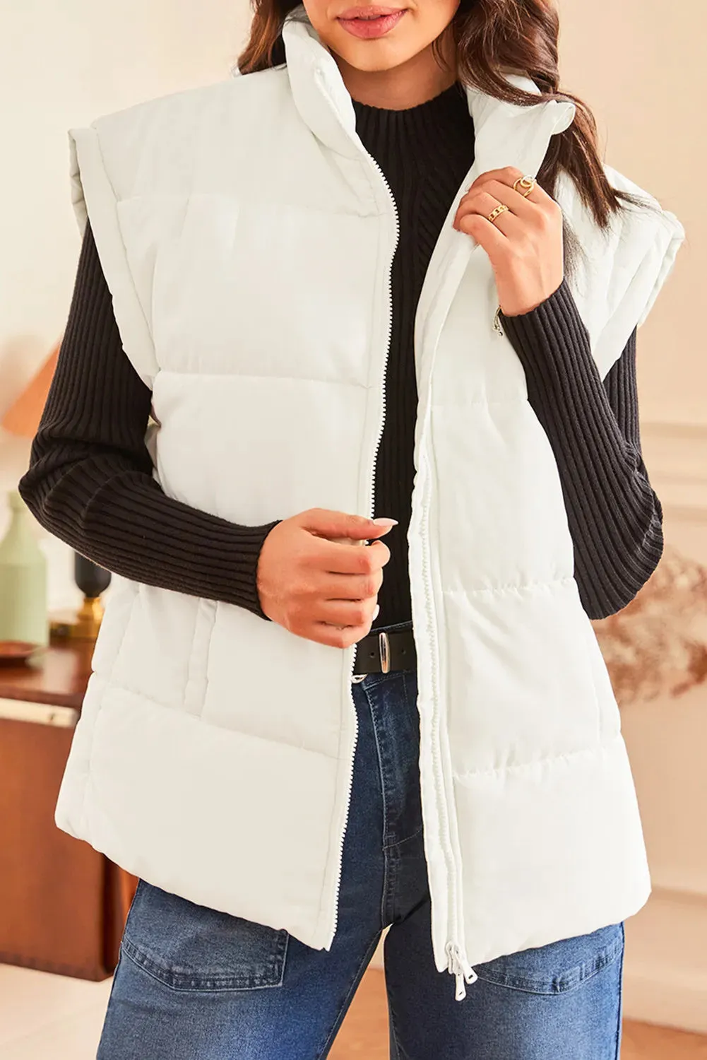 Women's beige oversized puffer vest with stand neck and front zipper, made from polyester, shown on a model
