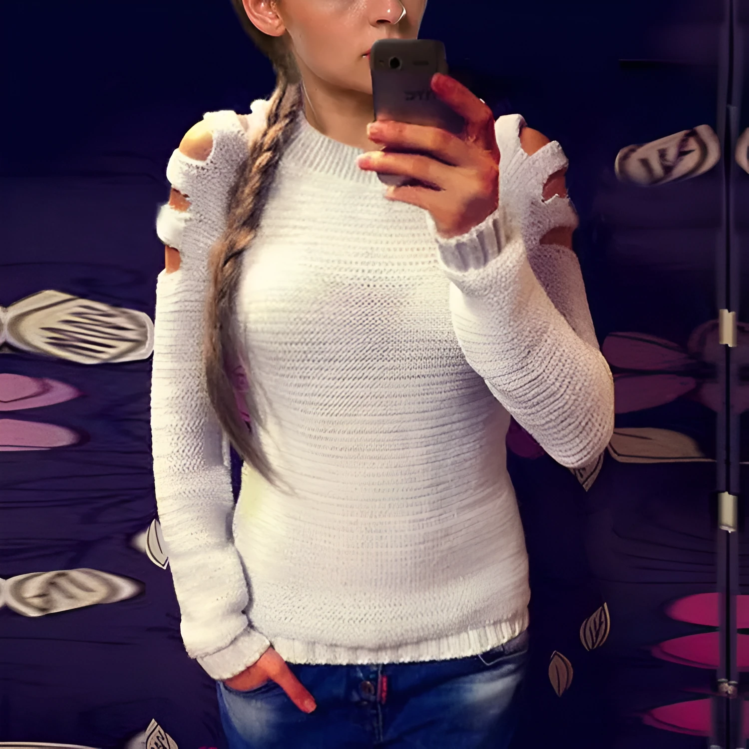 White women's hollow-out knitted long sleeve shirt with round neck on a hanger.