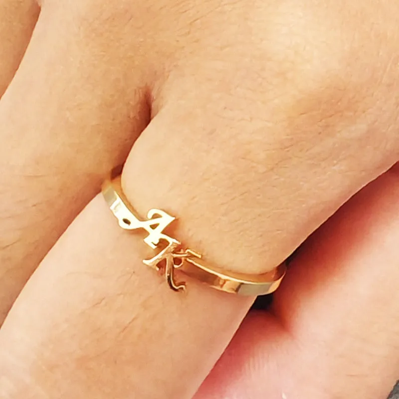 Customised 2 letters open ring in stainless steel with gold electroplated finish on a plain background