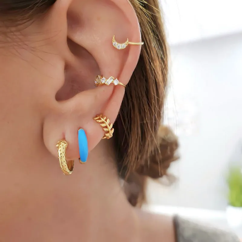A pair of oval glossy light green epoxy dome earrings on a silver-toned U-shaped geometric wire, against a neutral background.