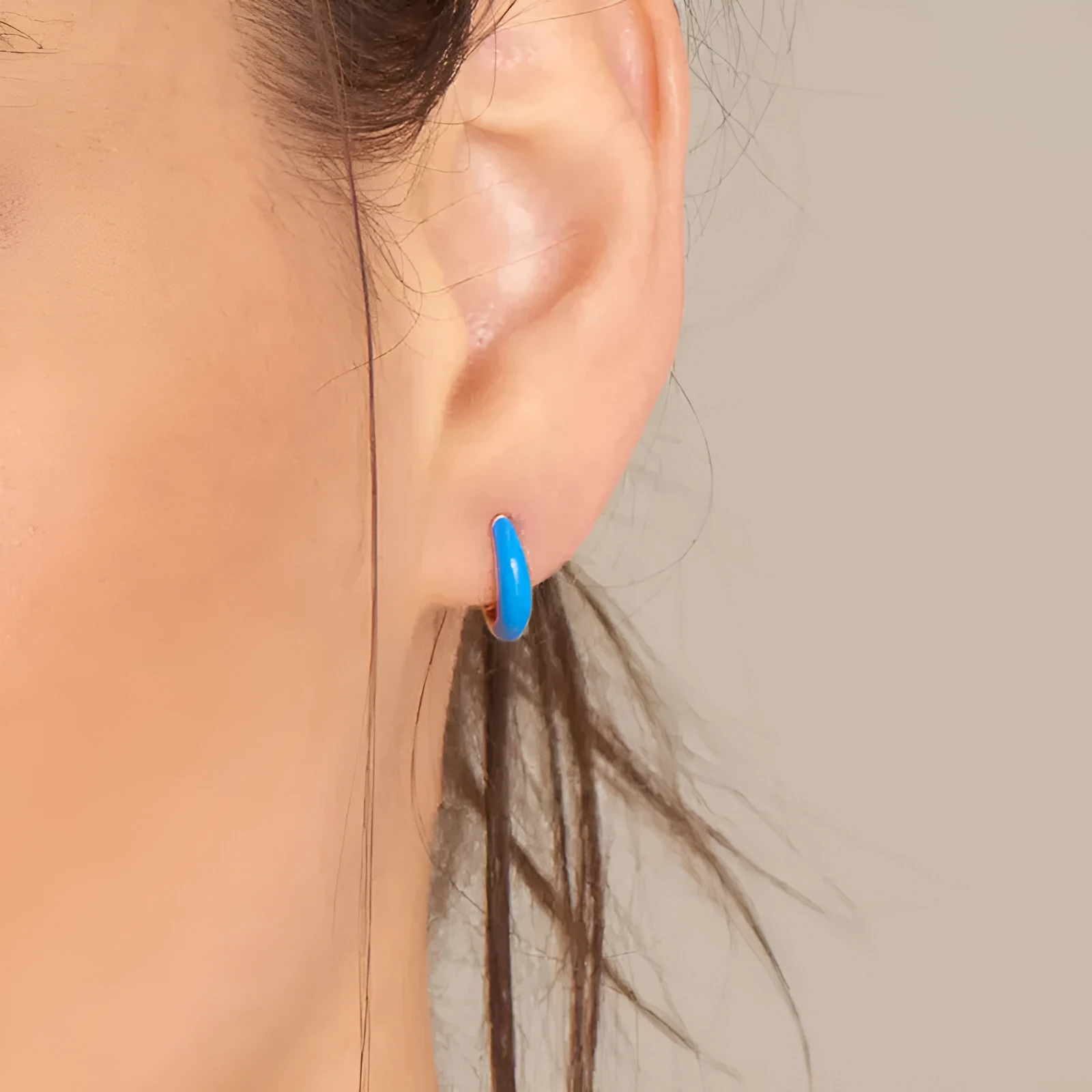 A pair of oval glossy light green epoxy dome earrings on a silver-toned U-shaped geometric wire, against a neutral background.