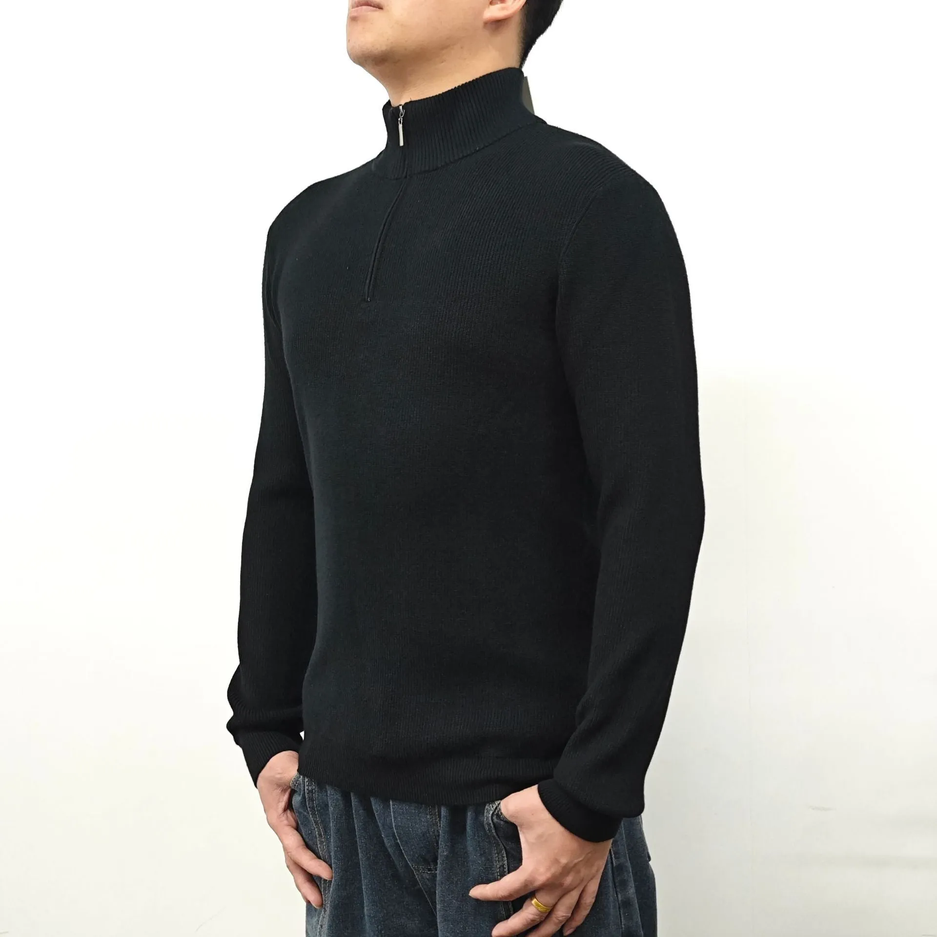 Men's black half-turtleneck zip sweater on a hanger, showing long sleeves and zip front detail.