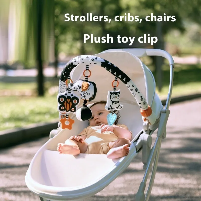Baby lathe clip hanging plush toy in black and white with pull vibration teether, attached to a cot