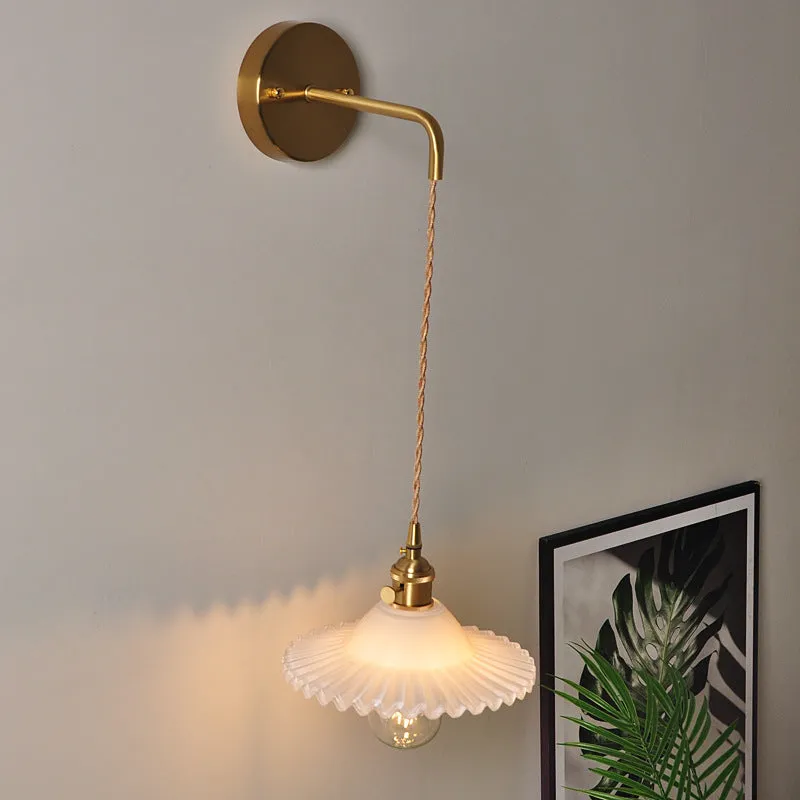 Retro brass lotus wall lamp with glass shade mounted on a beige wall, showcasing its copper arm and layered design.