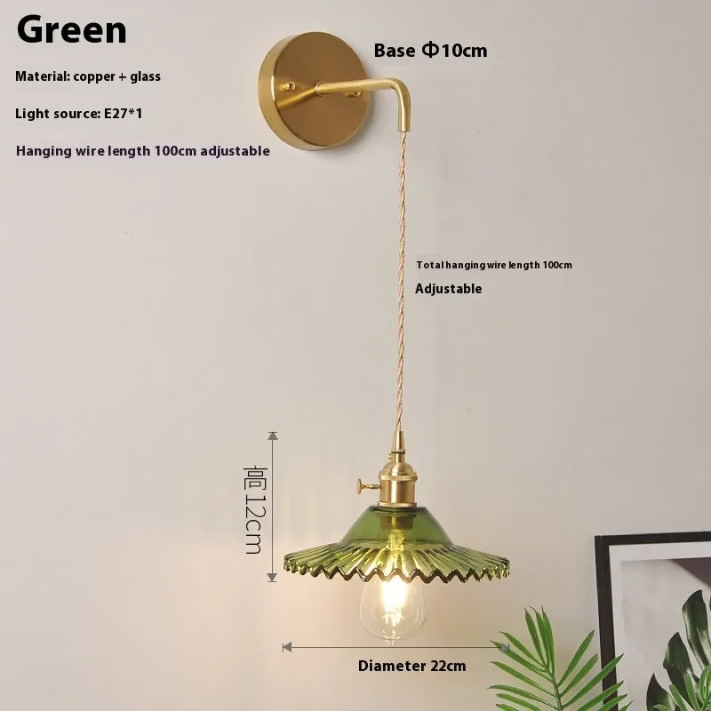 Retro brass lotus wall lamp with glass shade mounted on a beige wall, showcasing its copper arm and layered design.