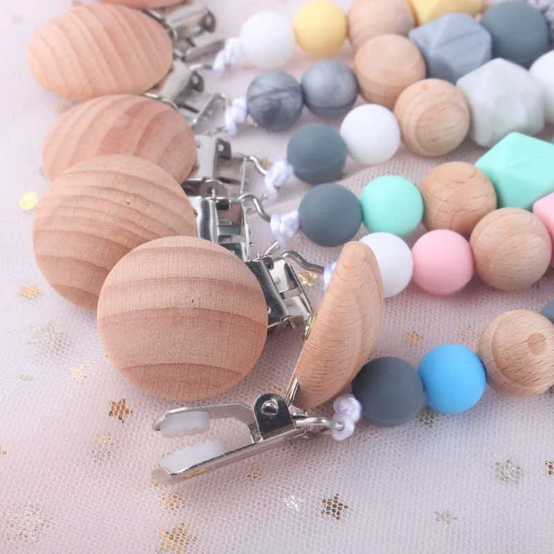 Baby silicone pacifier chain with beech wood beads in gradient colour, approximately 27cm long, clipped to a baby's clothing