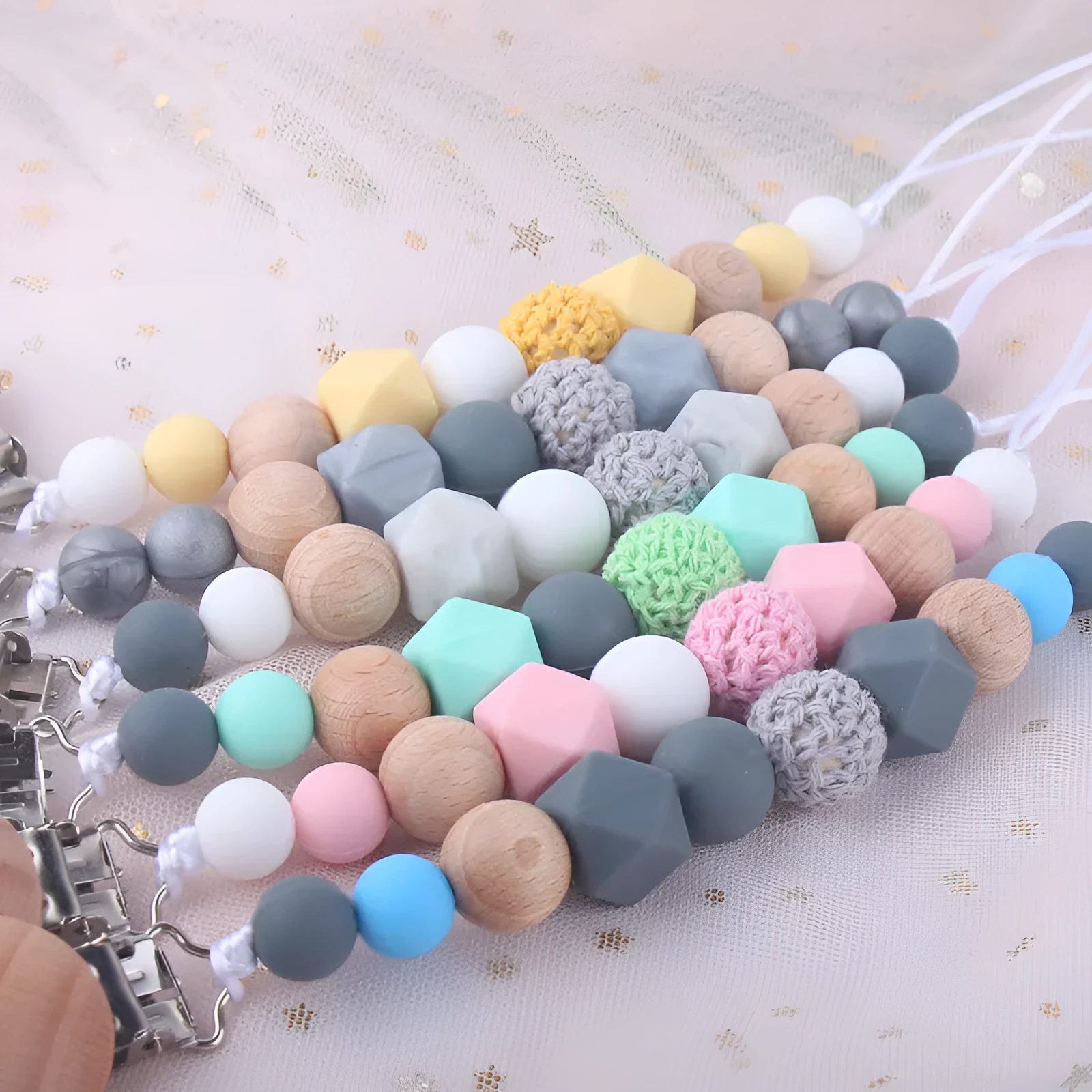 Baby silicone pacifier chain with beech wood beads in gradient colour, approximately 27cm long, clipped to a baby's clothing