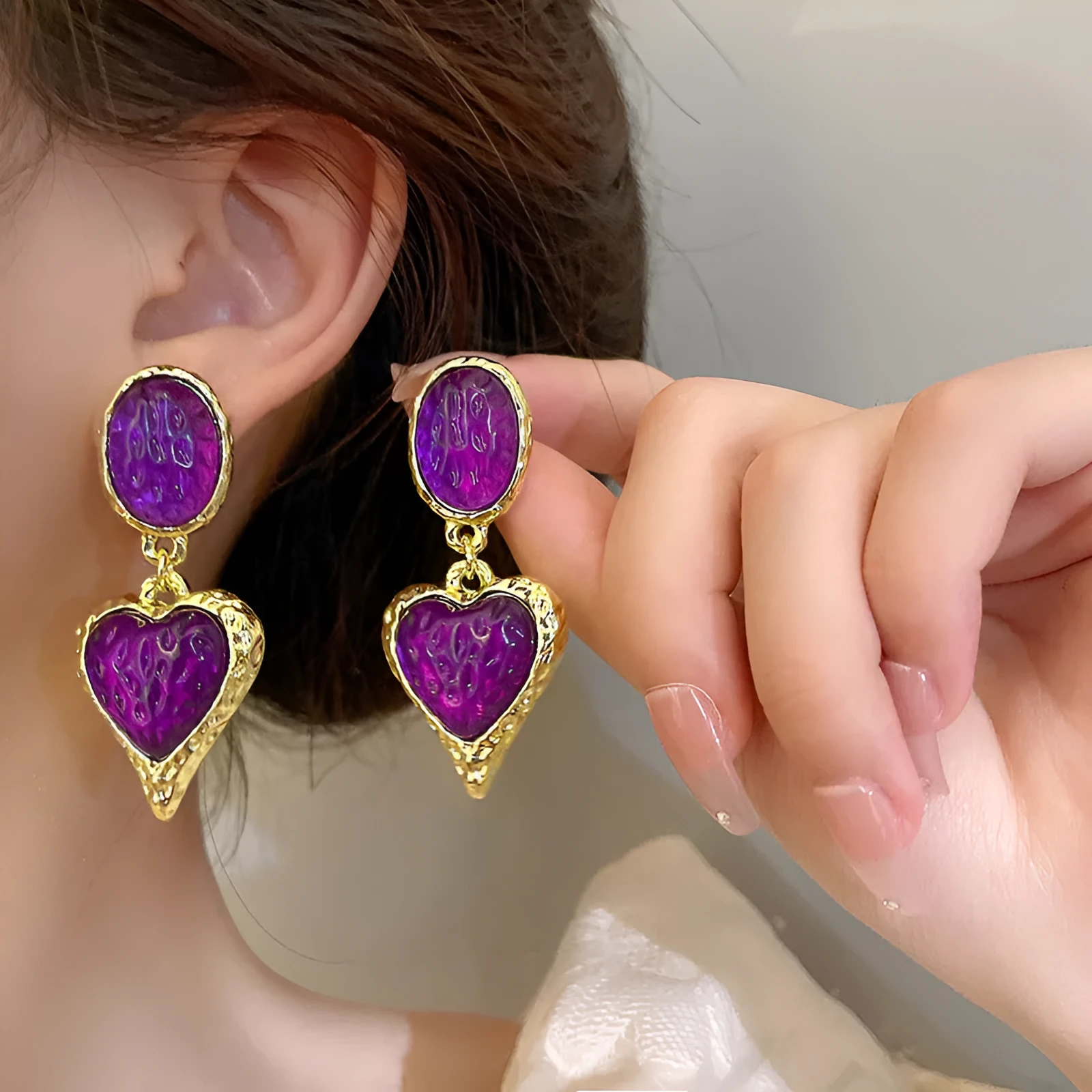 A pair of purple heart-shaped alloy stud earrings with a pleated oval texture and silver post.