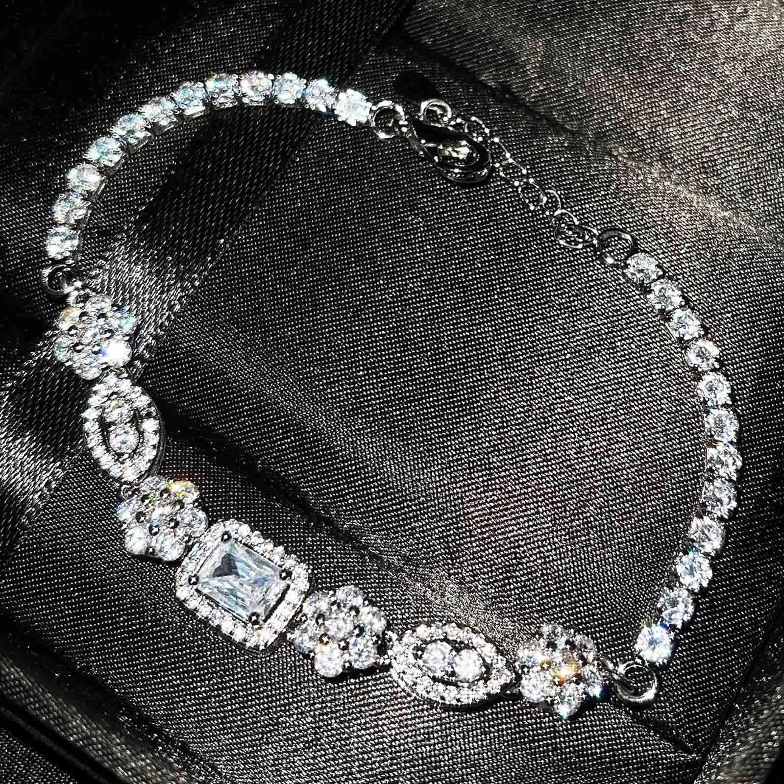 Women's geometric silver bracelet with inlaid white zircon stones on a wrist, showing adjustable clasp.