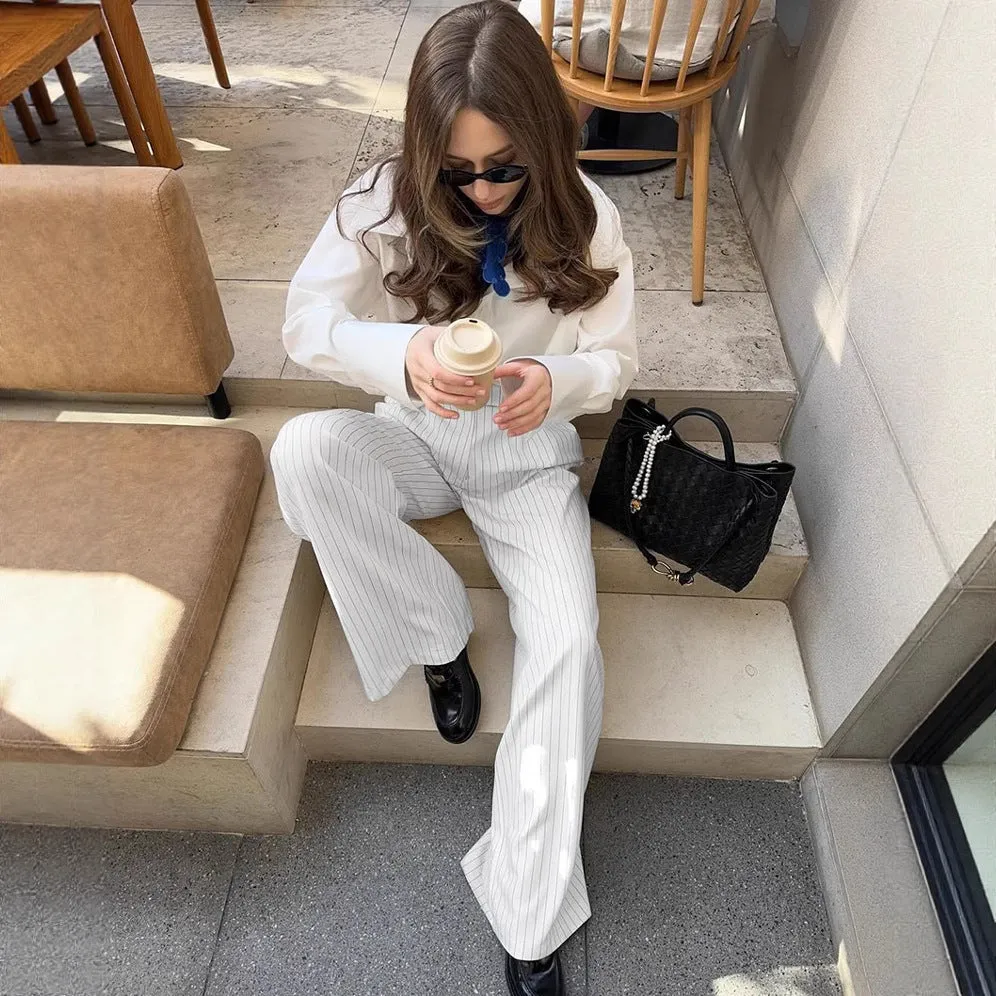 White striped loose-fit wide-leg trousers with a front zipper closure on a model.