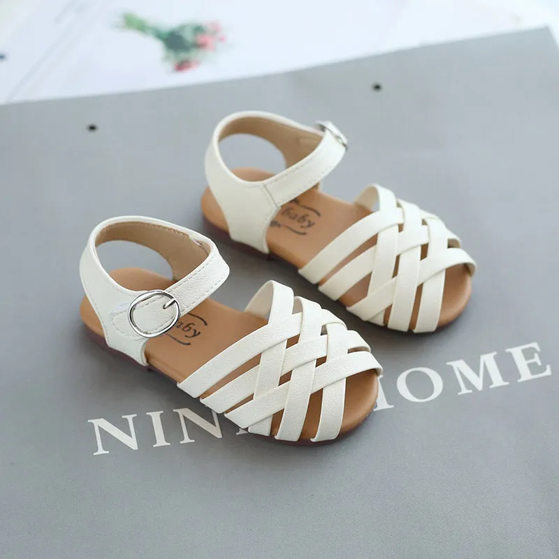 Kids buckle-toe soft sole woven sandals in white, black, and pink on a light background