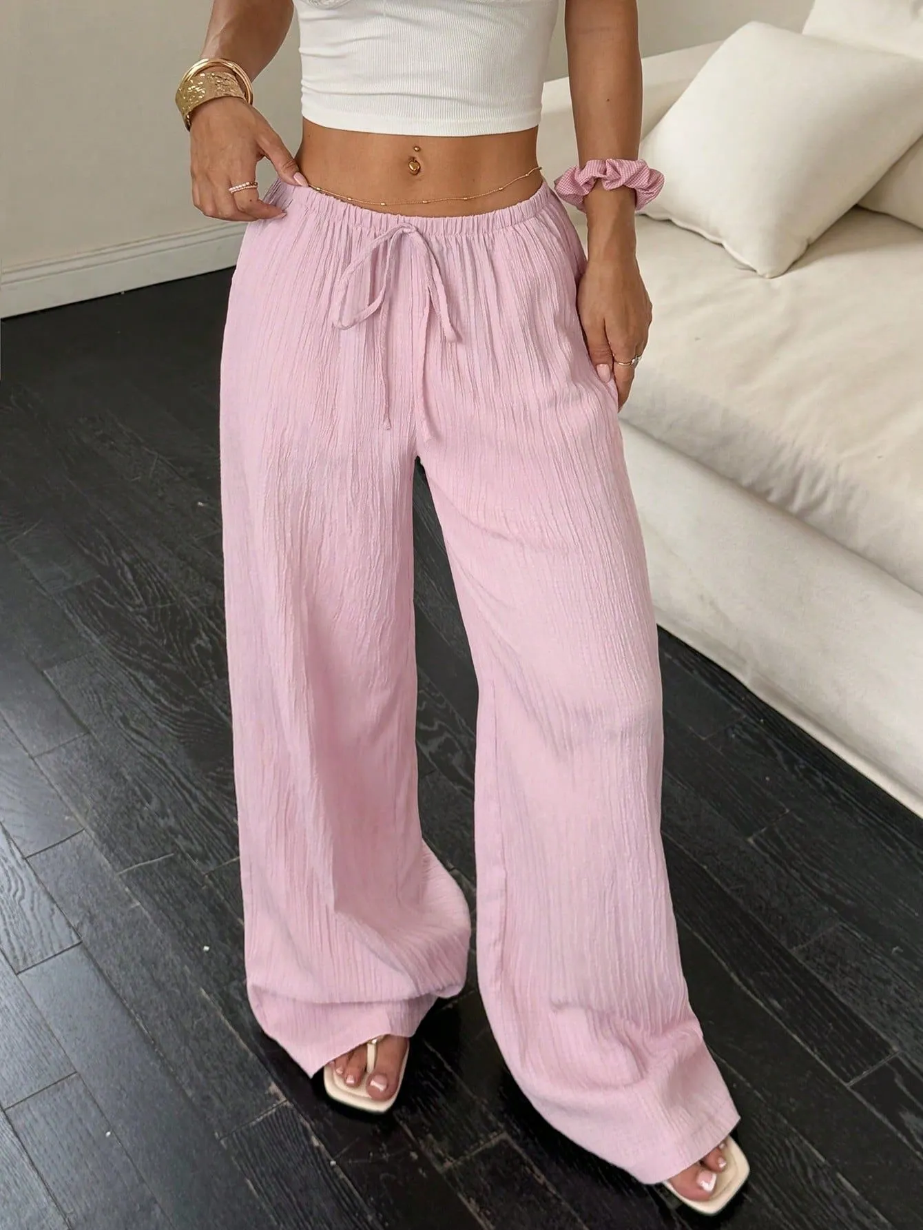 Women's black wide-leg trousers with a front lace-up waist detail on a mannequin.